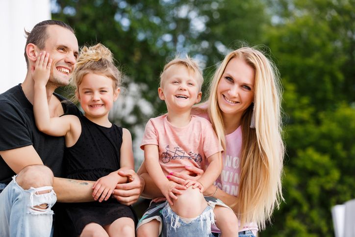 Family of four outside posing for family photos.