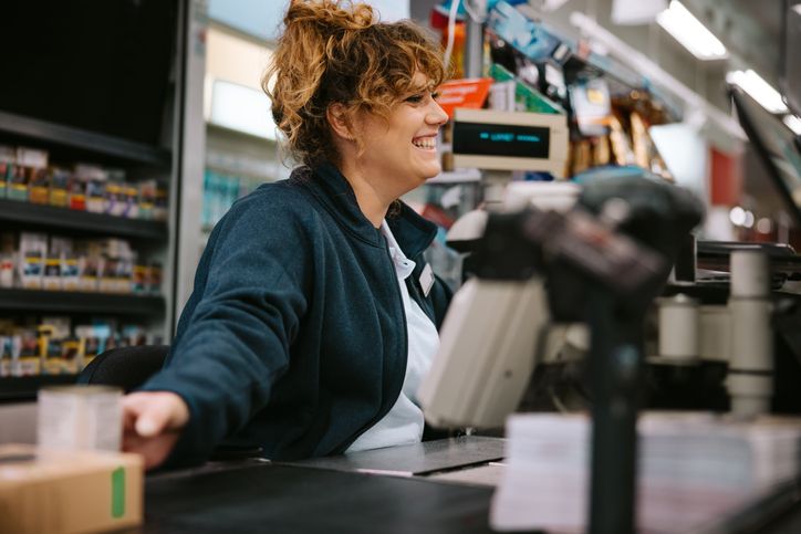 Happy woman cashier checking out customer.