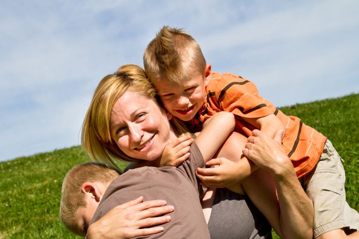 Mom outside with two small sons on a summer day.